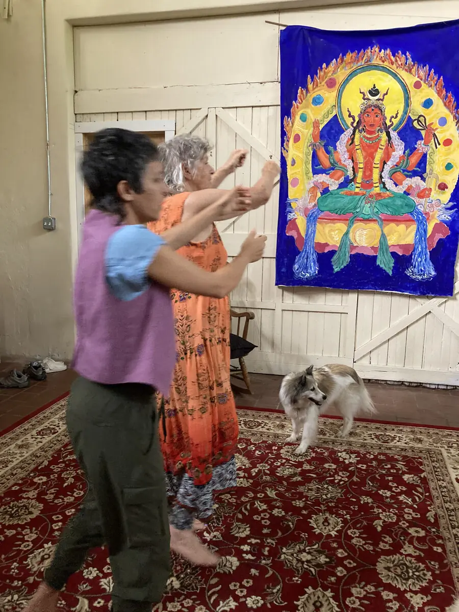 Two people working with a large, colorful tapestry indoors