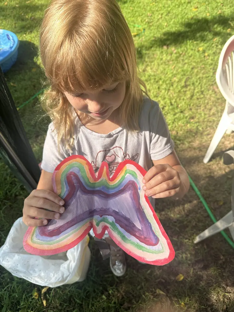 A child holding a handmade butterfly in the sun