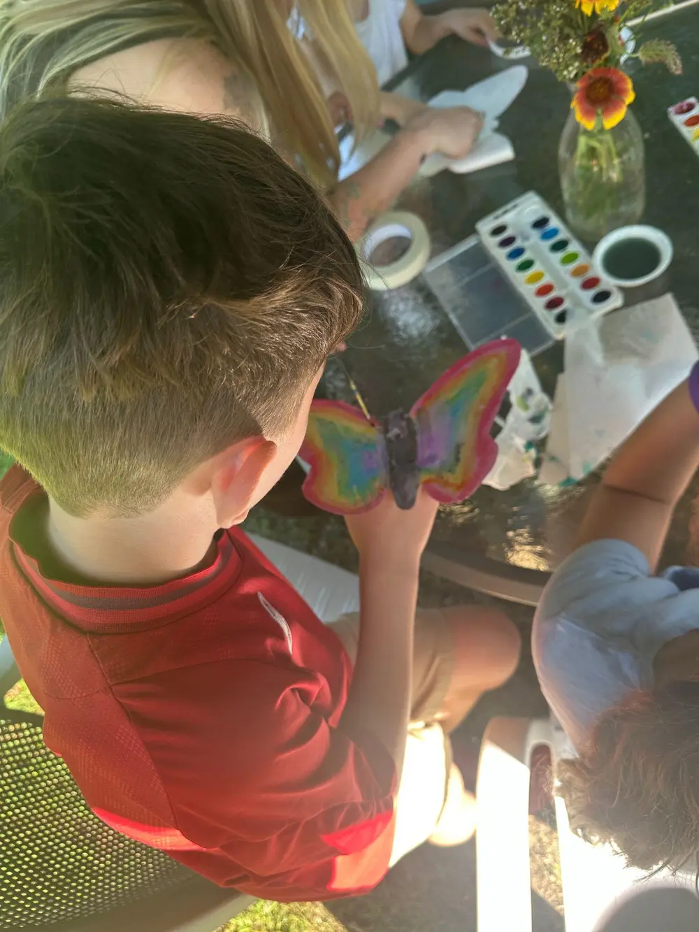 Children painting and making art together around a table