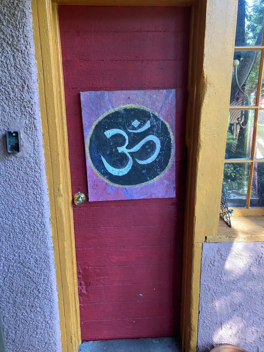 A golden Om symbol painted on a vibrant red door