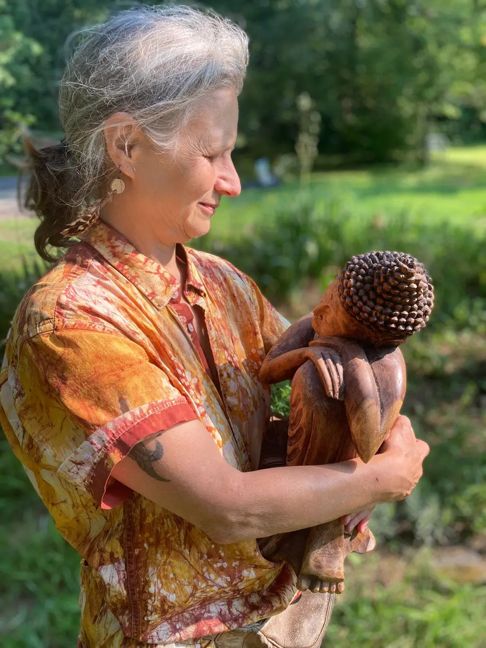 A community member holding a small Buddha statue in the garden