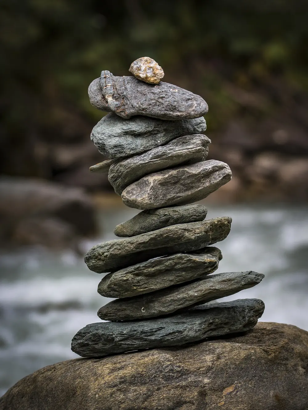 A balanced stack of smooth stones beside a flowing river