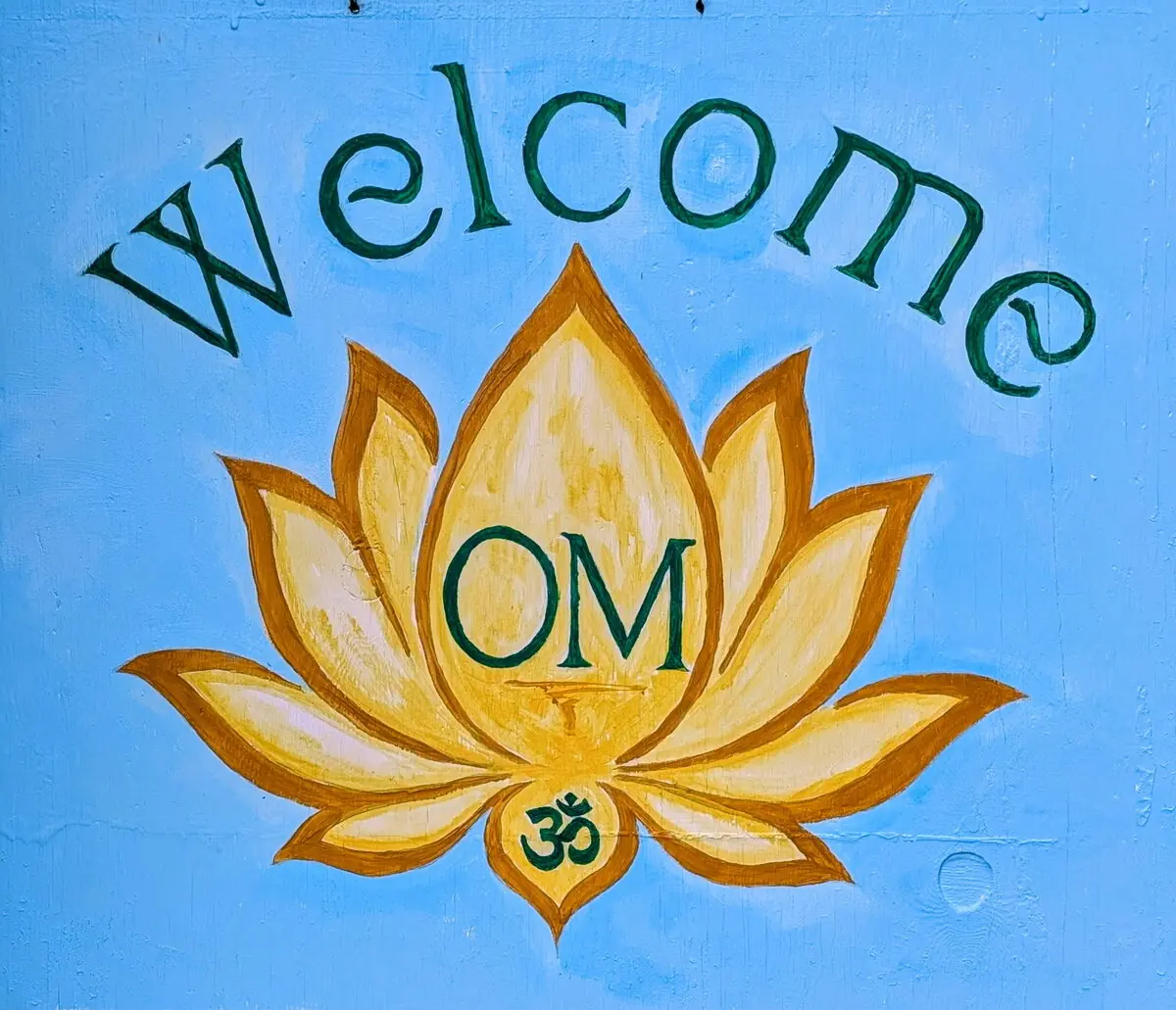 A hand-painted Welcome Om sign with a golden lotus